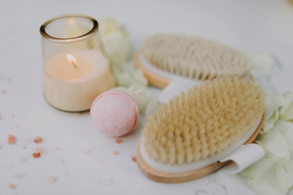pexels-photo-6724339-6724339 Flat lay of spa essentials including a lit candle, bath brush, and bath bomb for relaxation.
